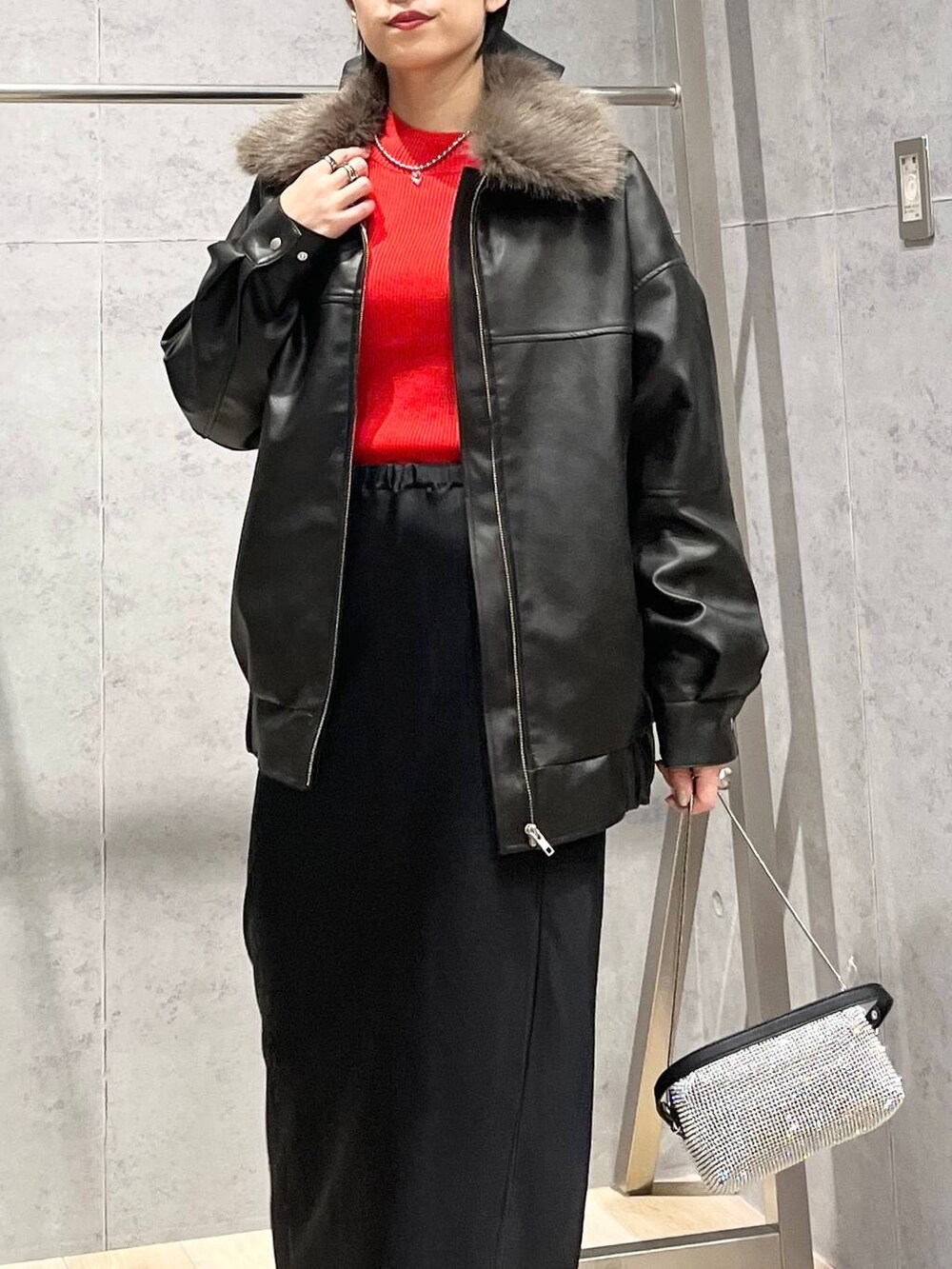 ブラック系のブーツ、オレンジ系のニット/セーター、ブラック系のスカートを着用したレディースの冬コーディネートの4枚目の写真