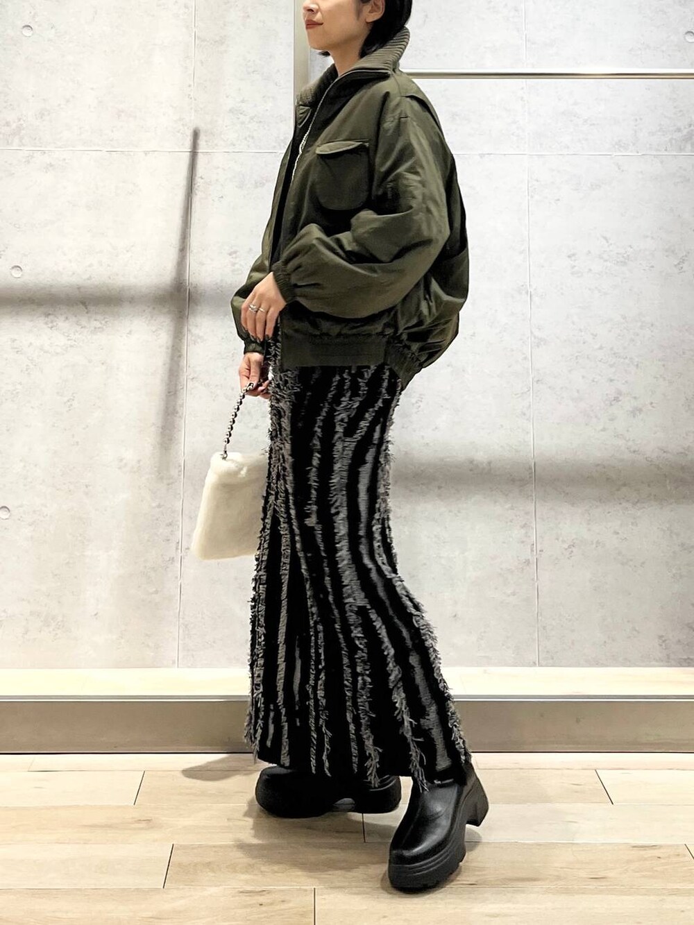 ブラック系のスカート、ブラック系のTシャツ/カットソー、ブラック系のブーツを着用したレディースの秋コーディネートの2枚目の写真