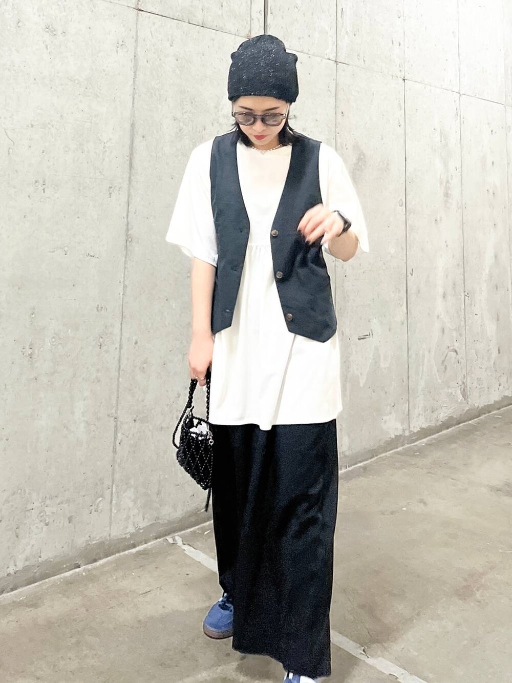 ブラック系のスラックス、ブラック系のショルダーバッグ、グレー系のベストを着用したレディースの夏コーディネートの7枚目の写真