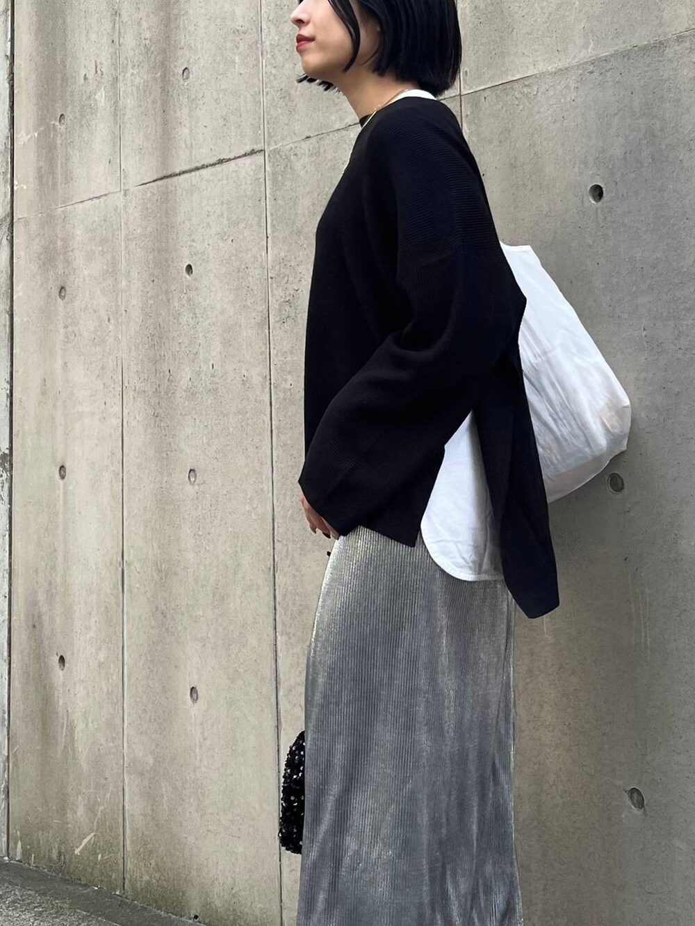 ブラック系のニット/セーター、ホワイト系のTシャツ/カットソー、シルバー系のスカートを着用したレディースの秋コーディネートの8枚目の写真