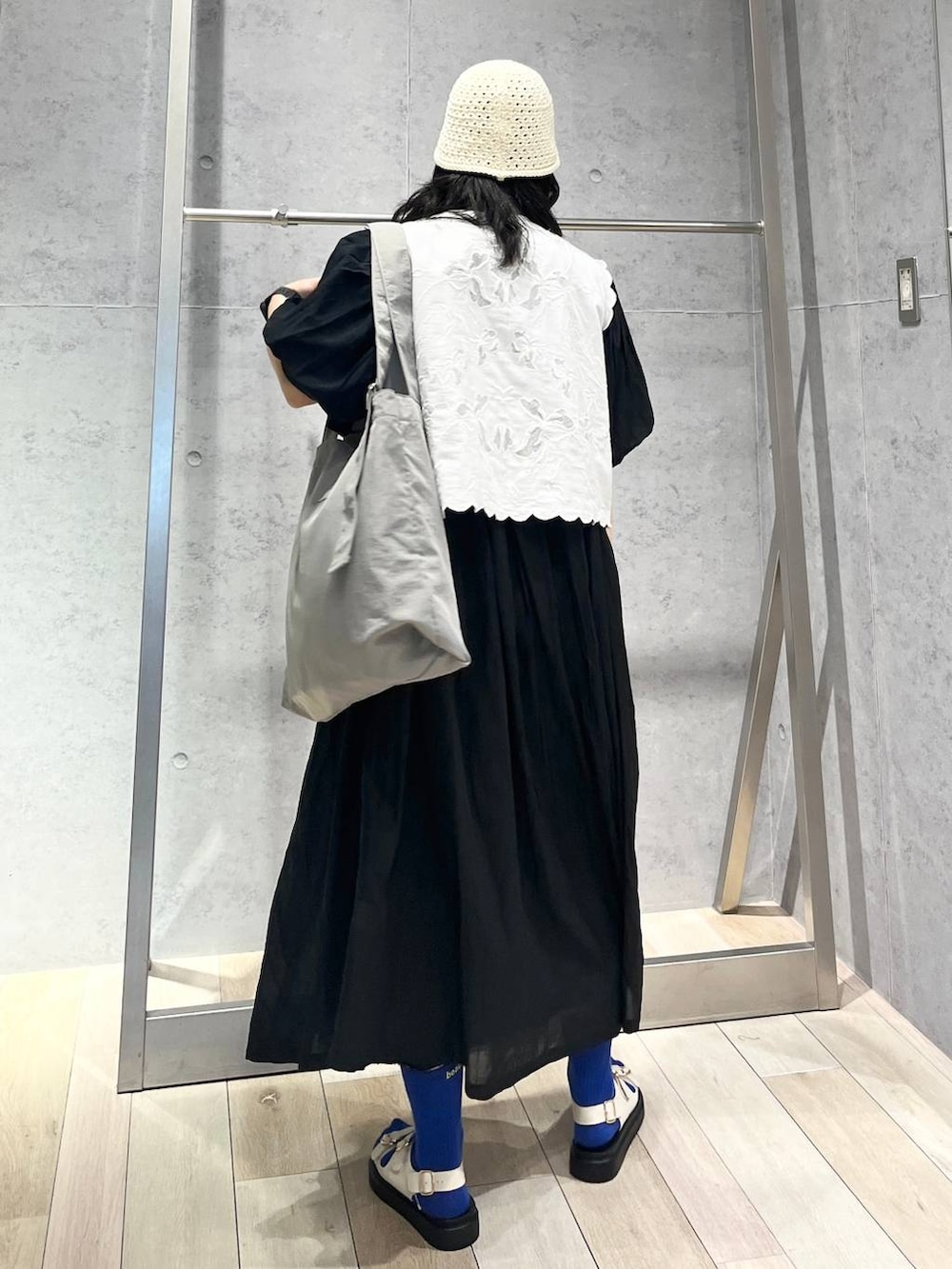 ブラック系のワンピース、ホワイト系のサンダル、ホワイト系のベストを着用したレディースの春コーディネートの5枚目の写真