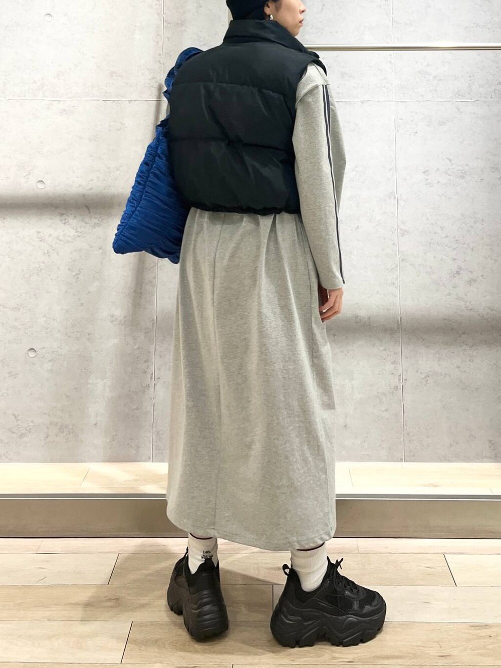 ブラック系のスニーカー、ブルー系のトートバッグ、ブラック系のベストを着用したレディースの冬コーディネートの3枚目の写真