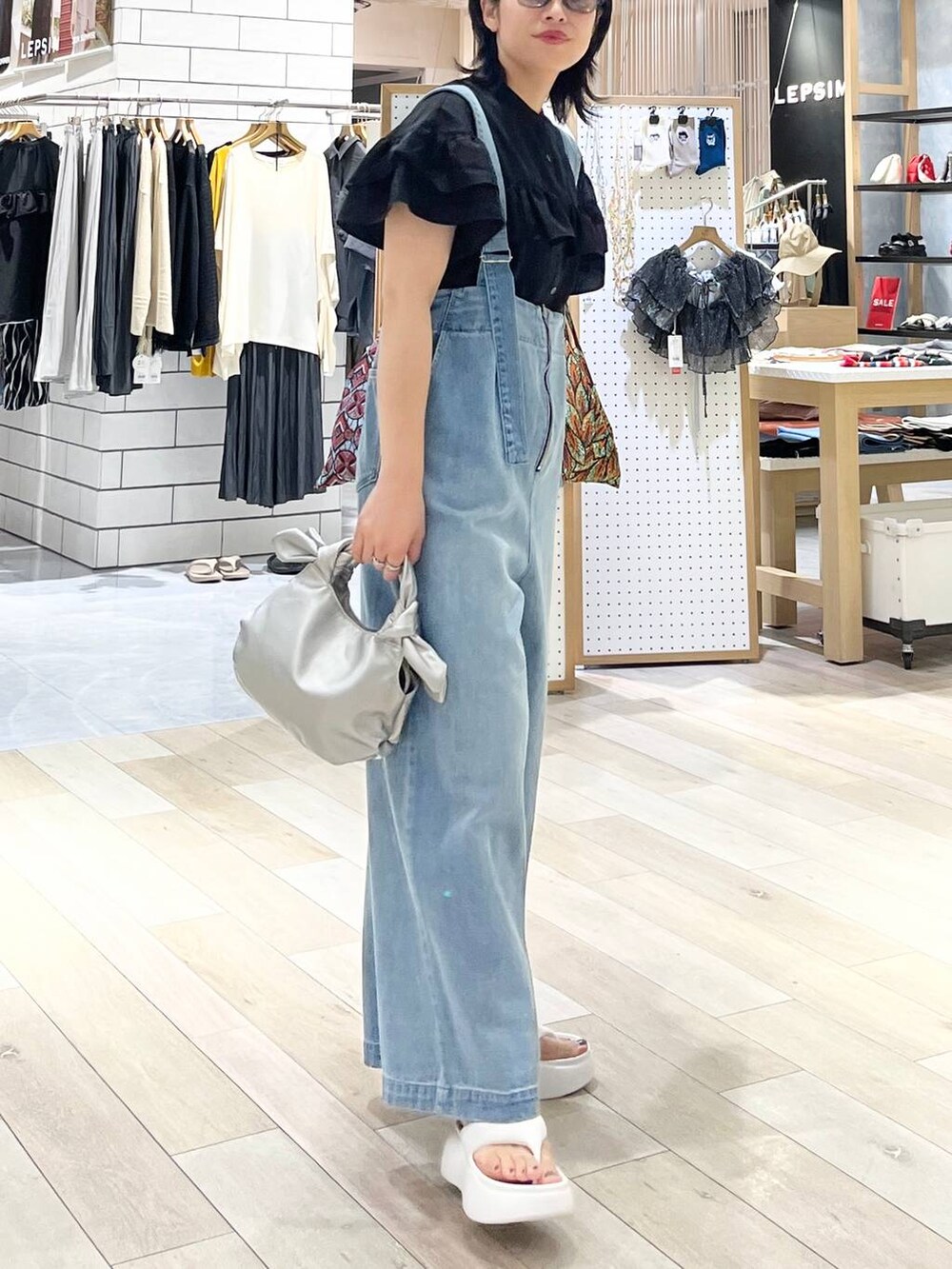 ホワイト系のサンダル、ブルー系のデニムパンツ、シルバー系のショルダーバッグを着用したレディースの夏コーディネートの3枚目の写真