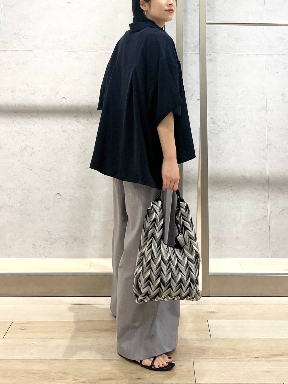 ブラック系のサンダル、ブラック系のハンドバッグ、ホワイト系のタンクトップを着用したレディースの夏コーディネートの4枚目の写真