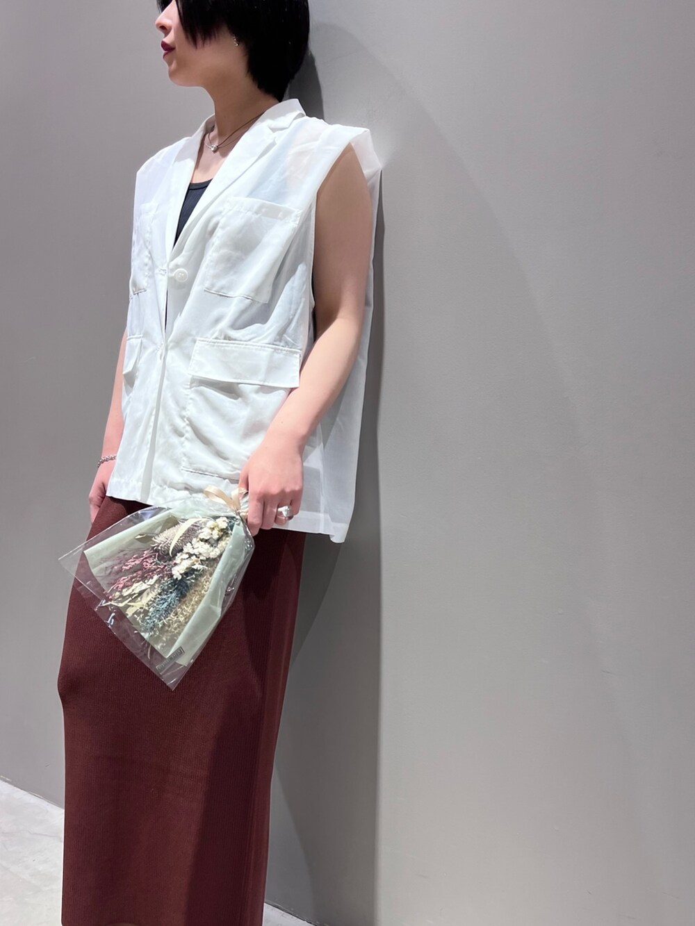 ホワイト系のベスト、ブラウン系のスカート、ブラック系のタンクトップを着用したレディースの春コーディネートの3枚目の写真