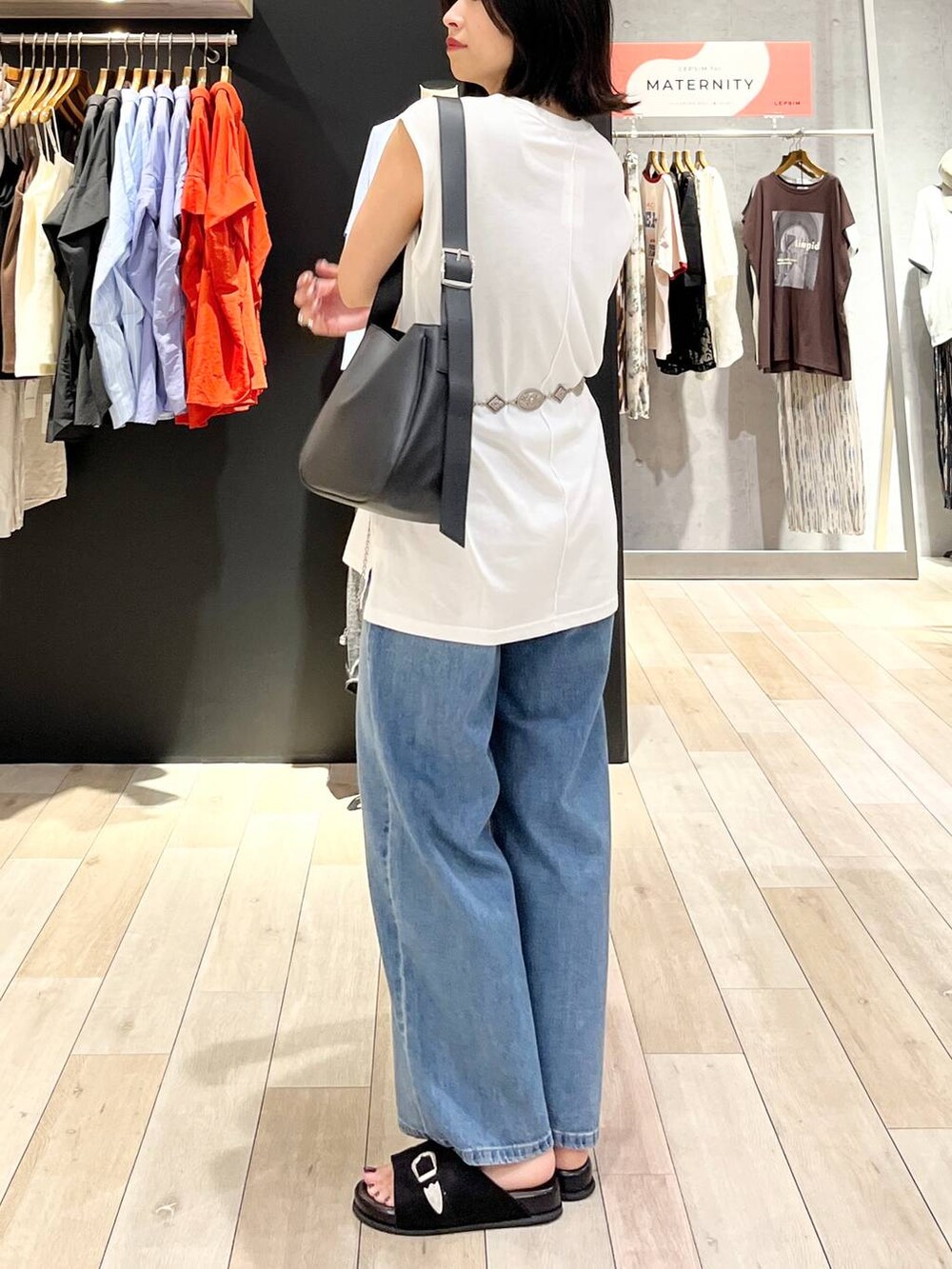 ブラック系のサンダル、ブルー系のデニムパンツ、ブラック系のショルダーバッグを着用したレディースの夏コーディネートの3枚目の写真