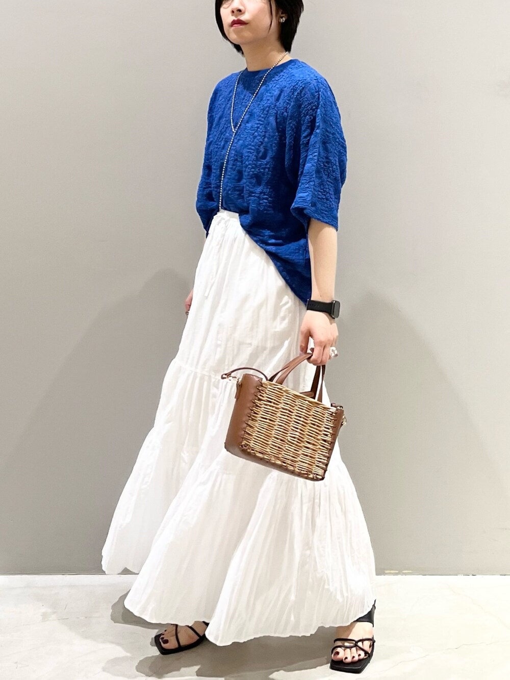 ブラック系のサンダル、ブラウン系のショルダーバッグ、ホワイト系のスカートを着用したレディースの夏コーディネートの10枚目の写真