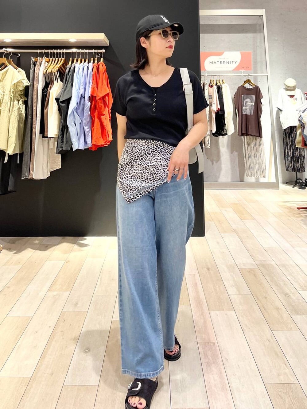 ブラック系のサンダル、ブルー系のデニムパンツ、グレー系のショルダーバッグを着用したレディースの夏コーディネートの2枚目の写真