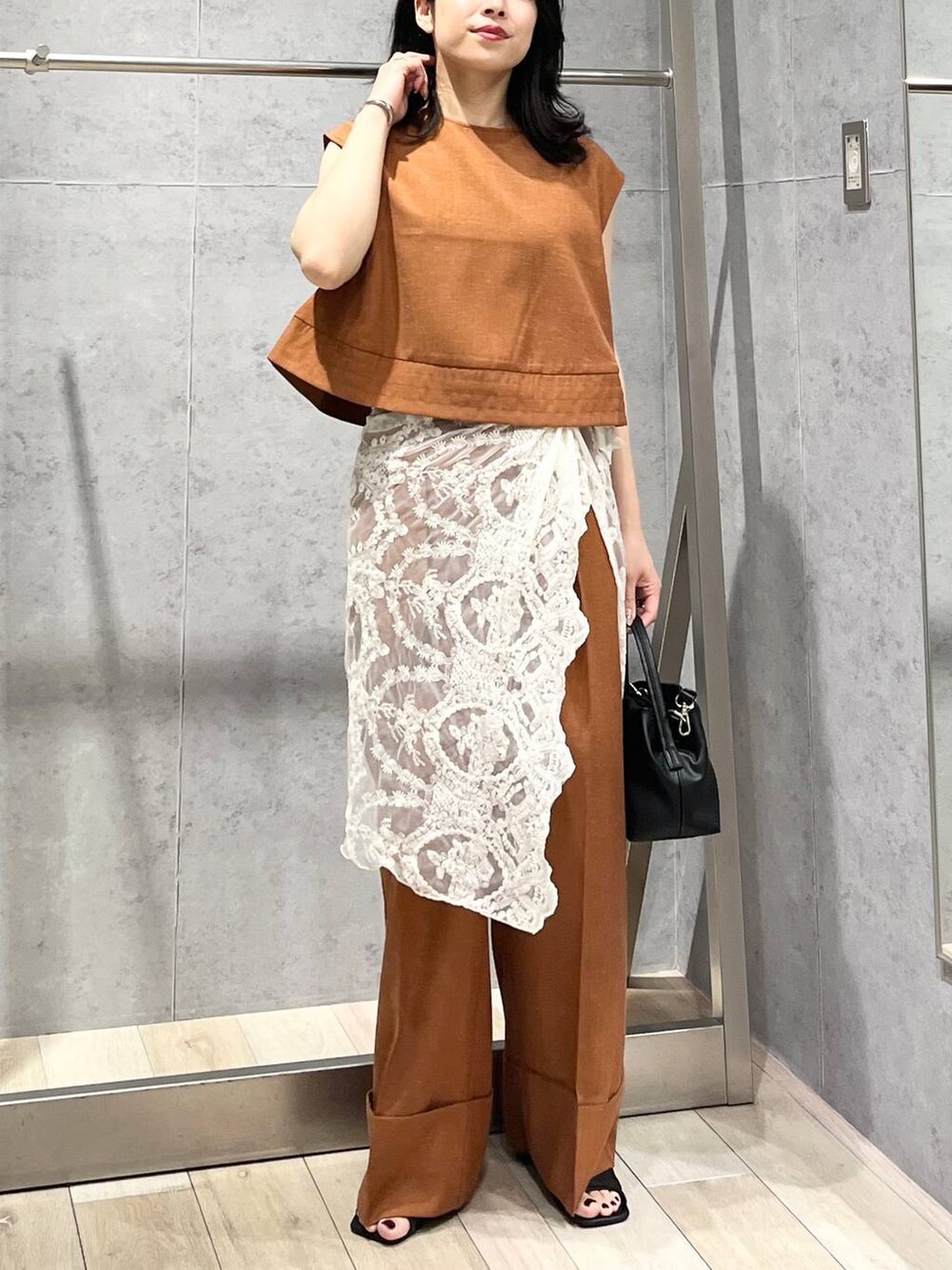 ブラック系のサンダル、オレンジ系のシャツ/ブラウス、ブラック系のショルダーバッグを着用したレディースの夏コーディネートの3枚目の写真