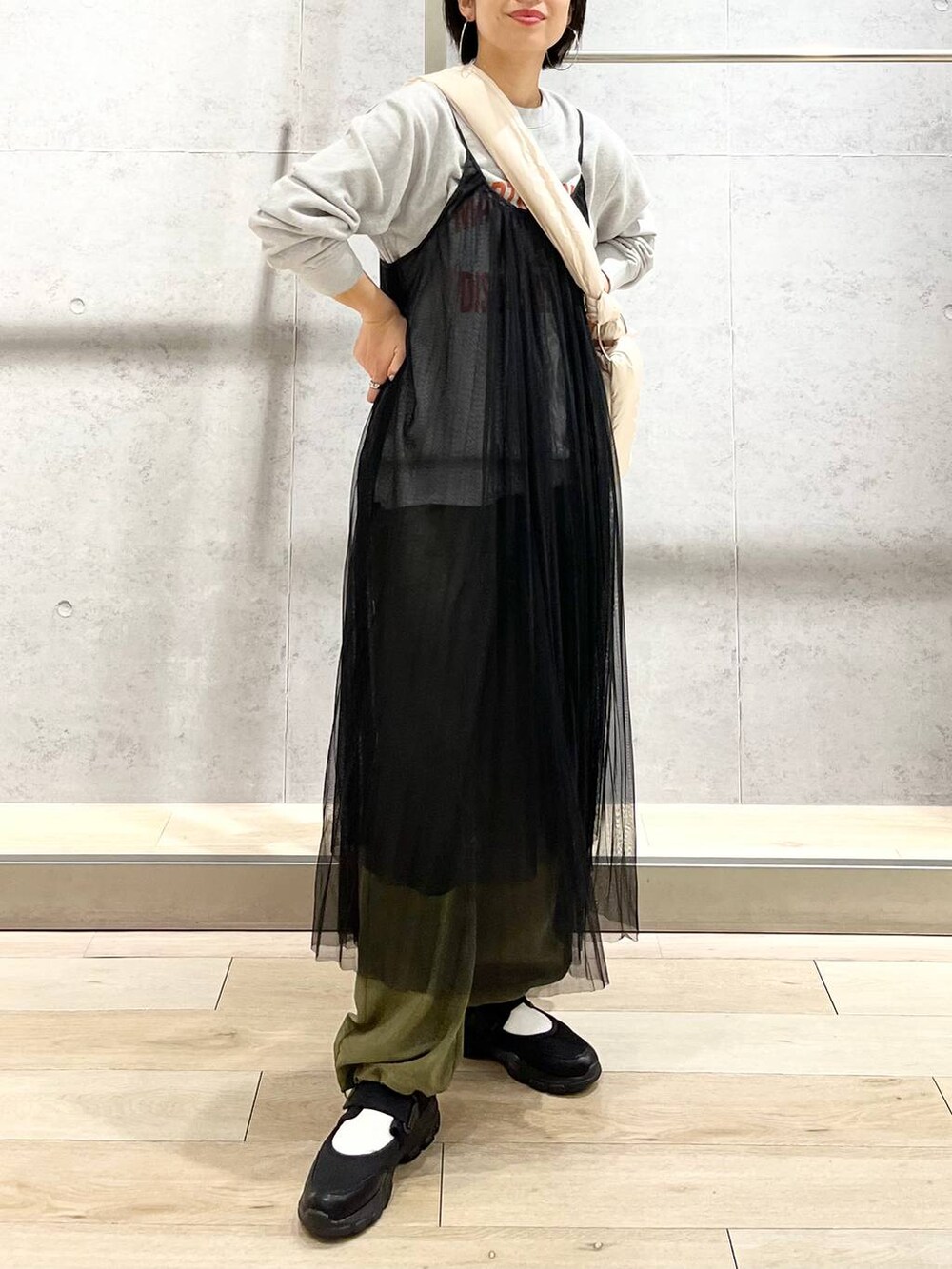 グレー系のスウェット、ブラック系のスニーカー、グリーン系のカーゴパンツを着用したレディースの秋コーディネートの2枚目の写真