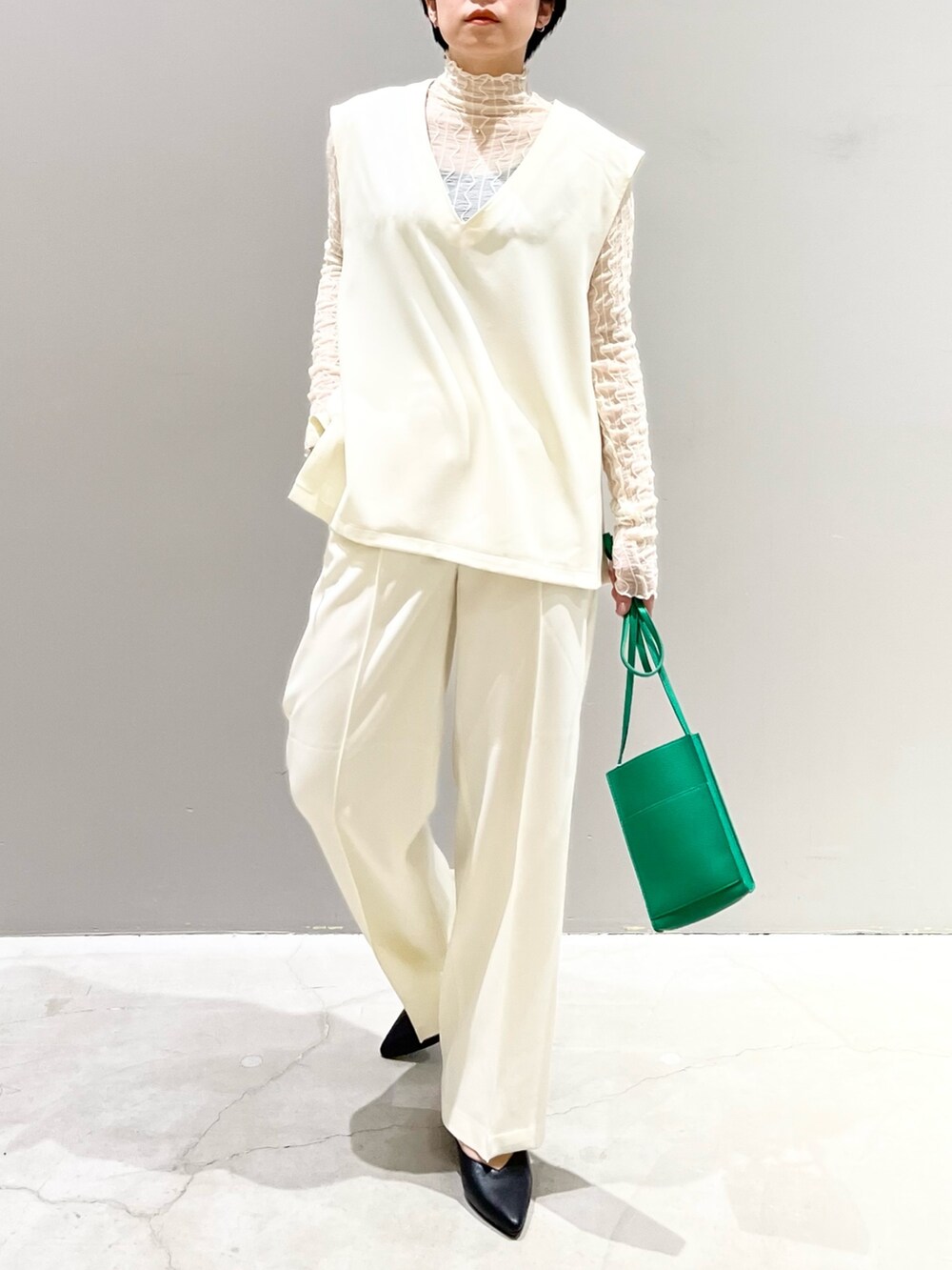 ホワイト系のベスト、グレー系のシューズ、グリーン系のバッグを着用したレディースの夏コーディネートの7枚目の写真