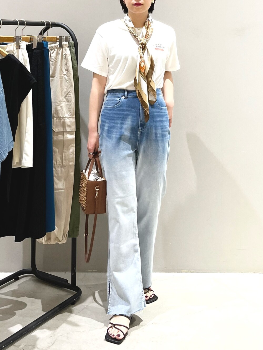 ブルー系のデニムパンツ、ブラック系のサンダル、ブラウン系のショルダーバッグを着用したレディースの夏コーディネートの2枚目の写真