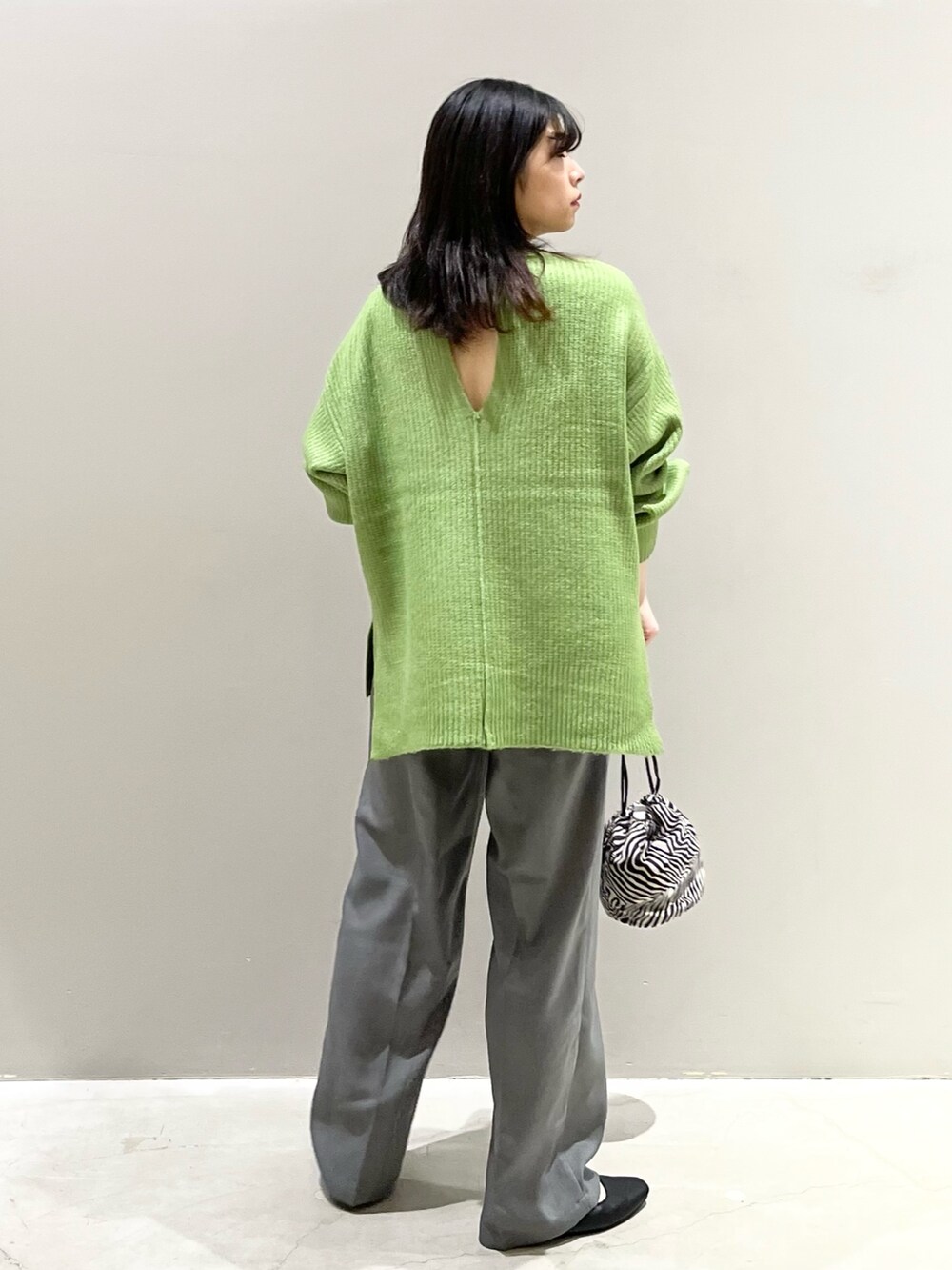 グリーン系のニット/セーター、ブラック系のパンプス、グレー系のパンツを着用したレディースの秋コーディネートの4枚目の写真