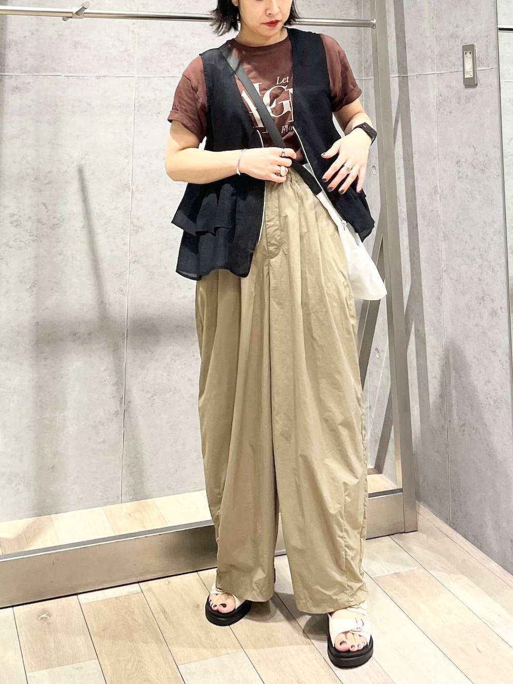 ホワイト系のサンダル、ブラック系のベスト、ブラウン系のTシャツ/カットソーを着用したレディースの夏コーディネートの2枚目の写真