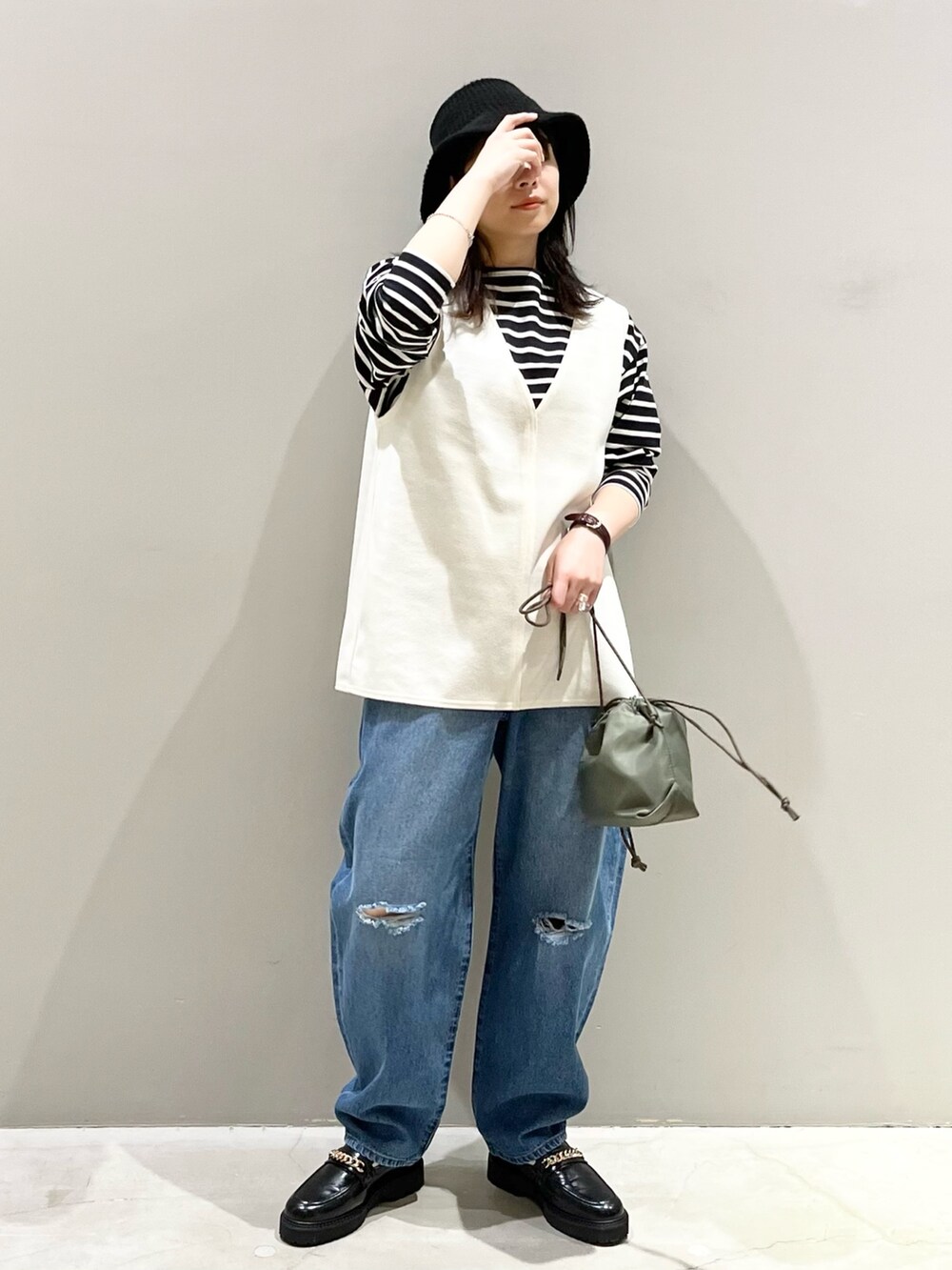 ブルー系のデニムパンツ、ブラック系のローファー、グリーン系のショルダーバッグを着用したレディースの冬コーディネートの2枚目の写真
