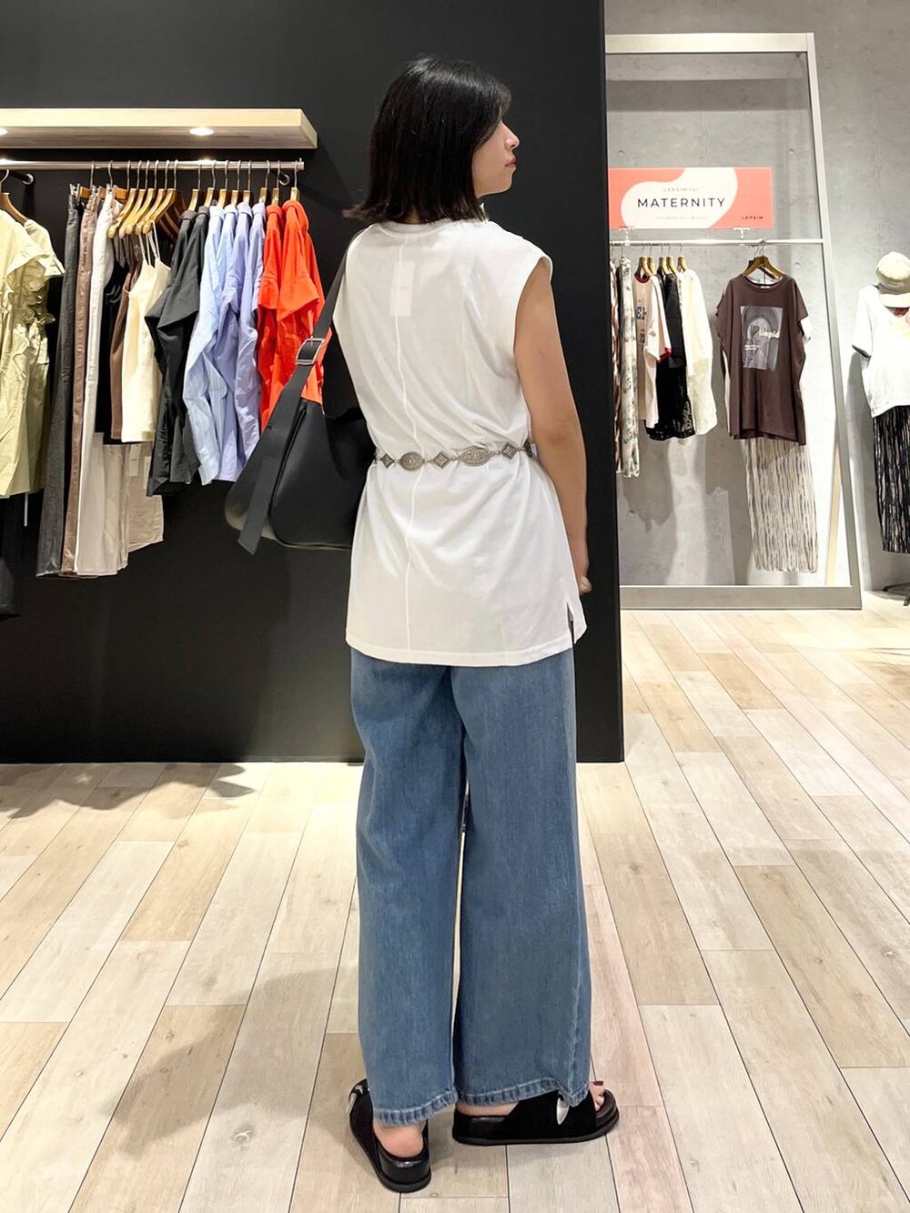 ブラック系のサンダル、ブルー系のデニムパンツ、ブラック系のショルダーバッグを着用したレディースの夏コーディネートの2枚目の写真