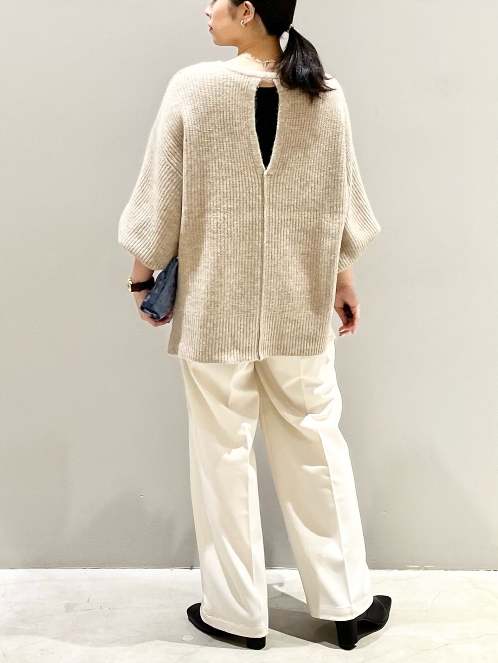 ベージュ系のニット/セーター、ホワイト系のスラックス、ブラック系のブーツを着用したレディースの秋コーディネートの2枚目の写真