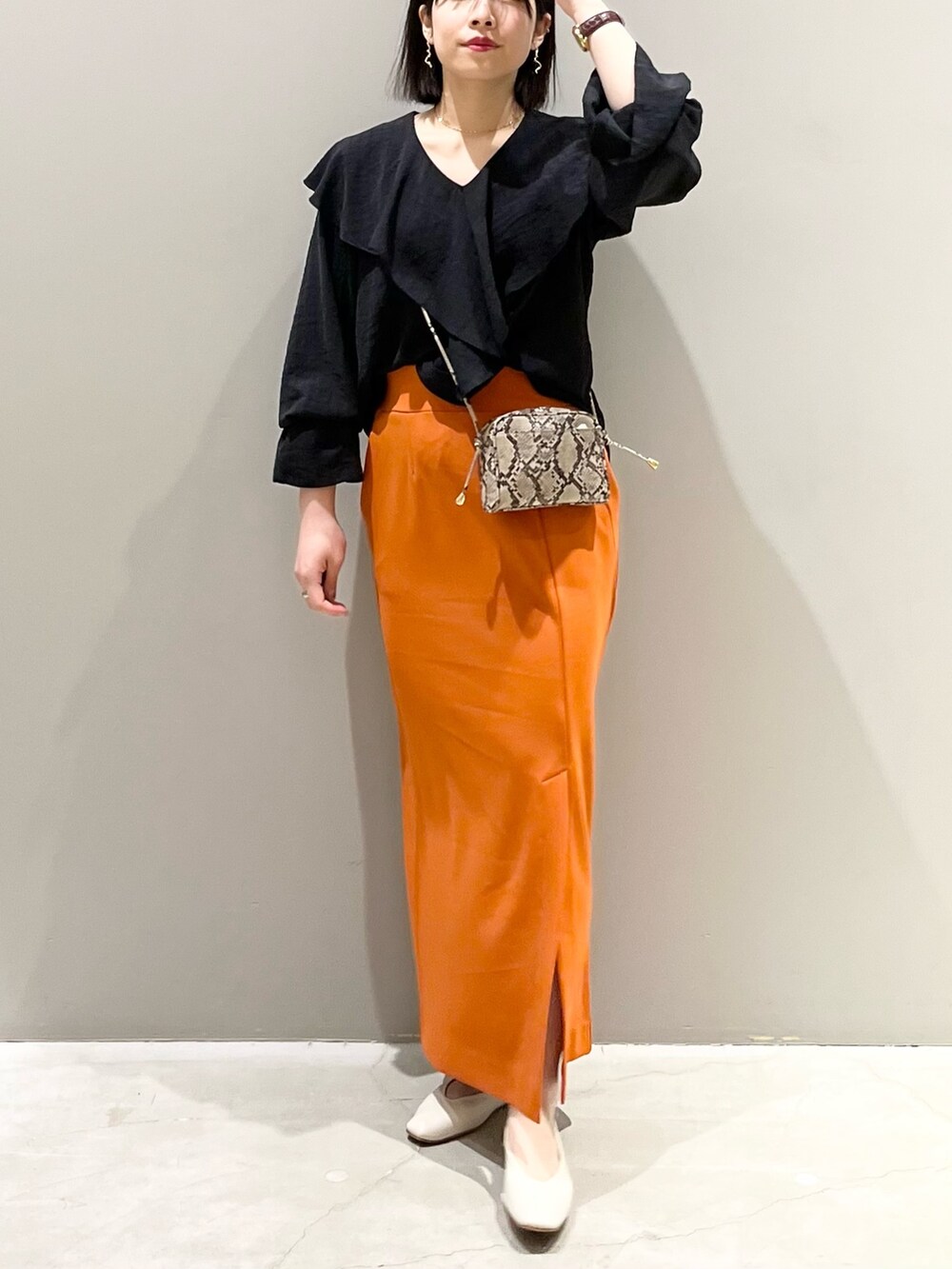 オレンジ系のスカート、ホワイト系のパンプス、その他のショルダーバッグを着用したレディースの春コーディネートの6枚目の写真