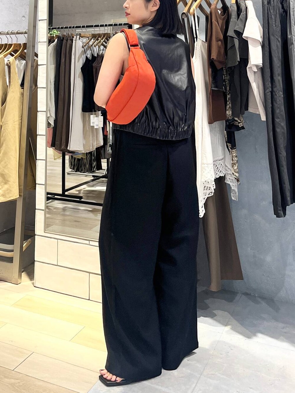 ホワイト系のタンクトップ、ブラック系のその他パンツ、オレンジ系のショルダーバッグを着用したレディースの夏コーディネートの3枚目の写真