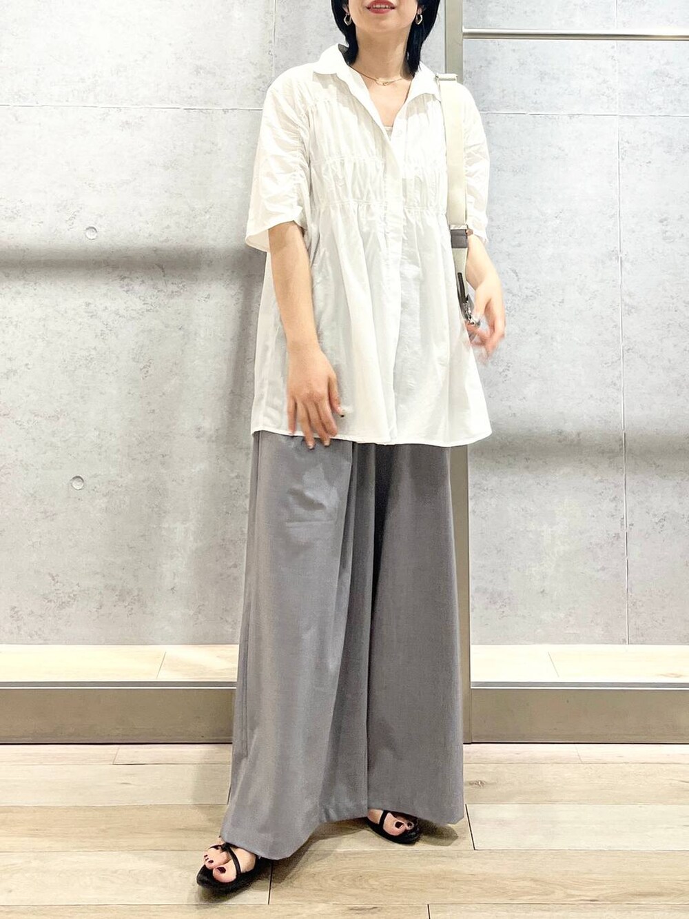 ブラック系のサンダル、ブラック系のハンドバッグ、グレー系のスラックスを着用したレディースの夏コーディネートの5枚目の写真