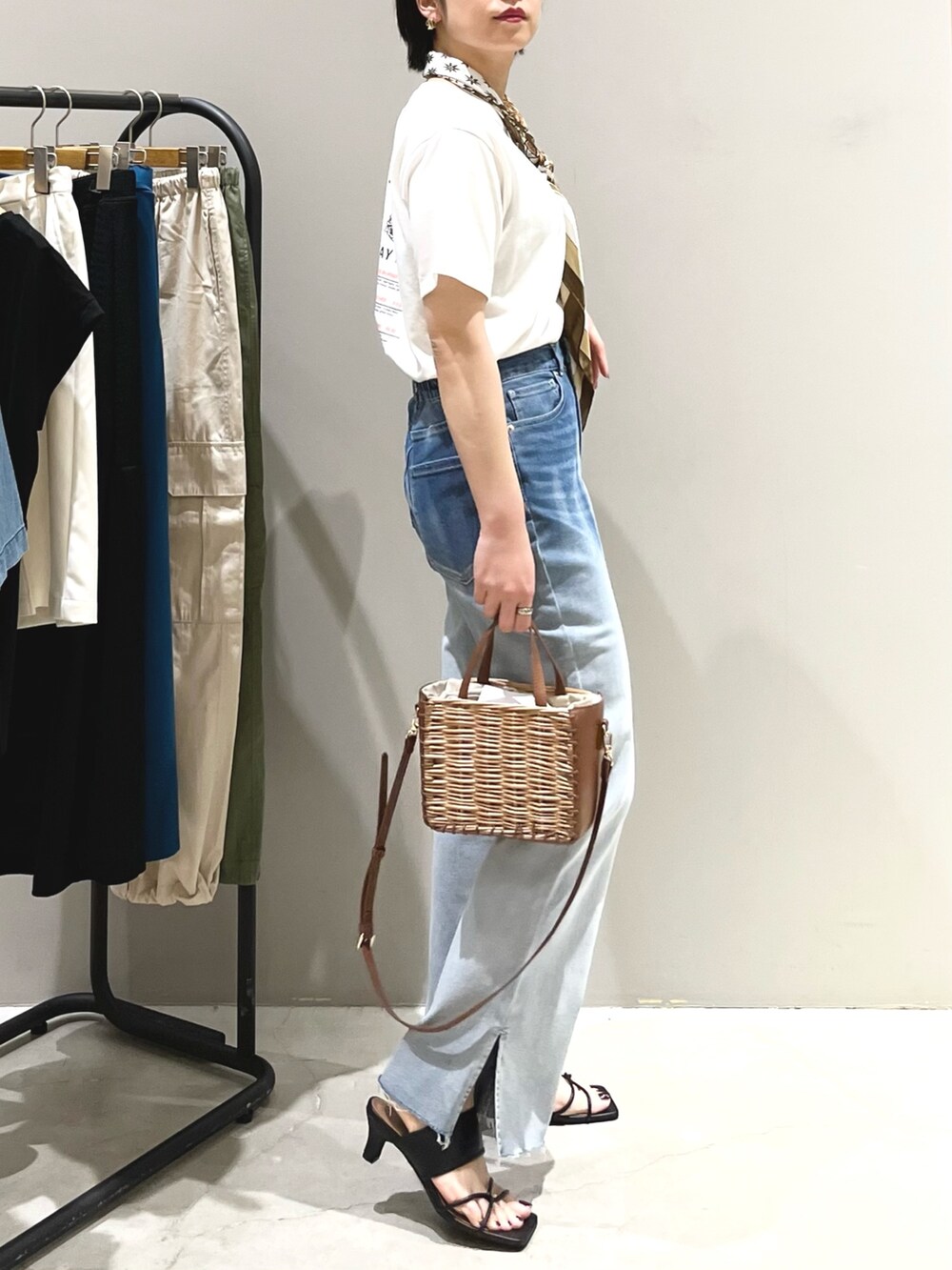 ブルー系のデニムパンツ、ブラック系のサンダル、ブラウン系のショルダーバッグを着用したレディースの夏コーディネートの4枚目の写真