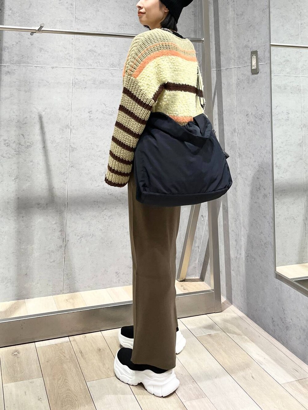 ブラウン系のスカート、ブラウン系のニット/セーター、ブラック系のブーツを着用したレディースの秋コーディネートの4枚目の写真