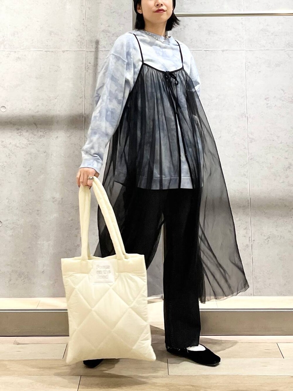 ブラック系のバレエシューズ、ホワイト系のトートバッグ、グレー系のデニムパンツを着用したレディースの冬コーディネートの2枚目の写真