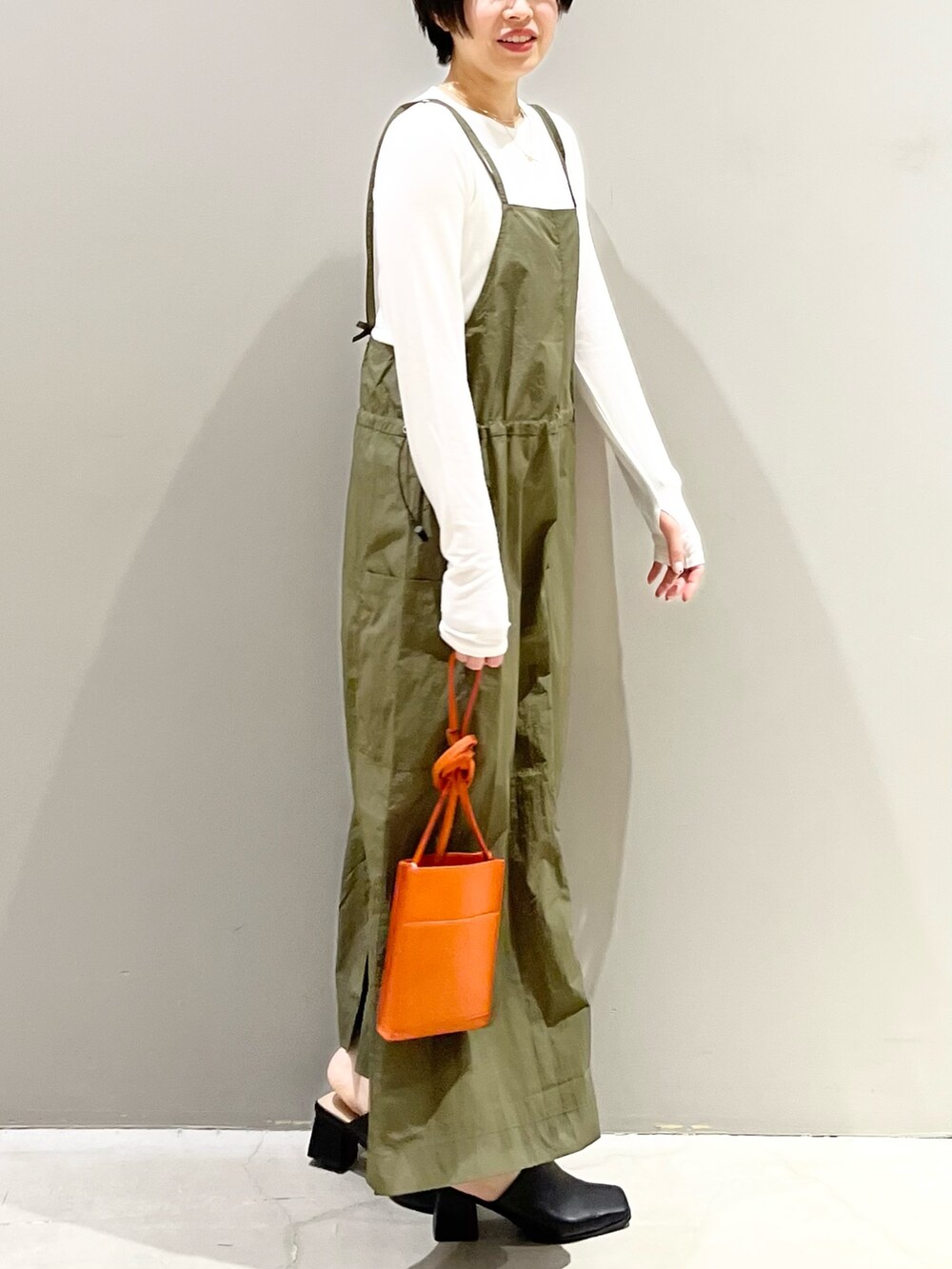 グリーン系のワンピース、オレンジ系のバッグ、ブラック系のサンダルを着用したレディースの春コーディネートの3枚目の写真