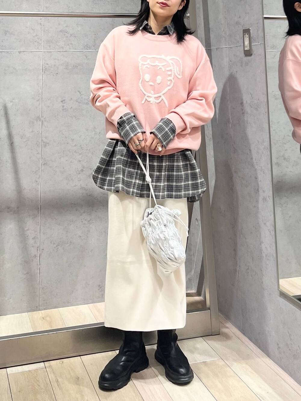 シルバー系のショルダーバッグ、ホワイト系のスカート、ブラック系のブーツを着用したレディースの冬コーディネートの2枚目の写真