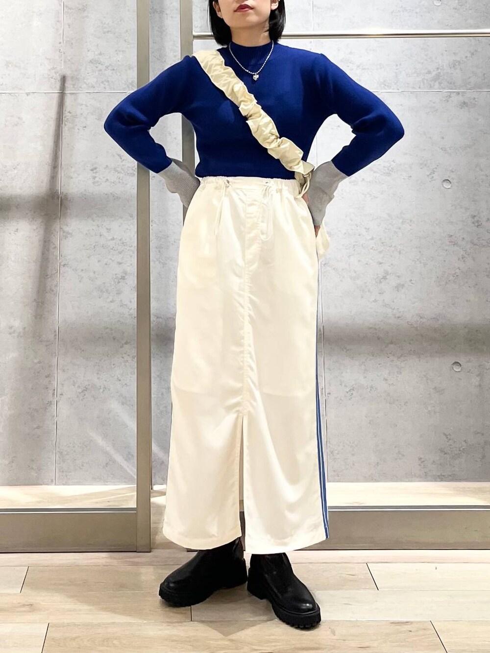 ブラック系のブーツ、ホワイト系のショルダーバッグ、ホワイト系のスカートを着用したレディースの冬コーディネートの5枚目の写真