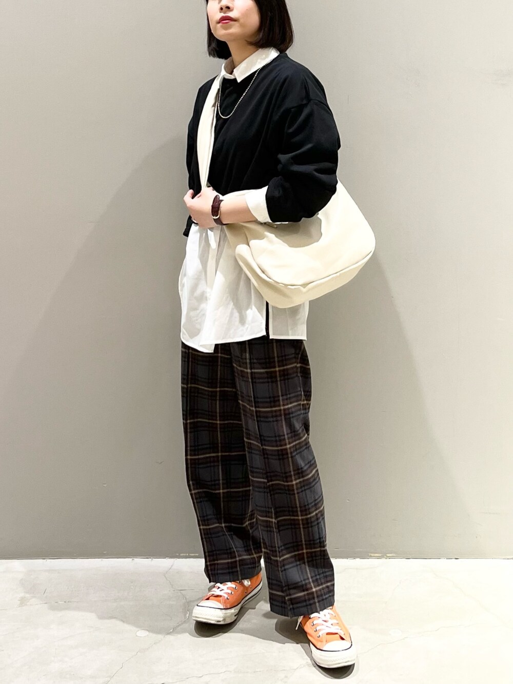 オレンジ系のスニーカー、ブラウン系のスラックス、ホワイト系のバッグを着用したレディースの春コーディネートの2枚目の写真