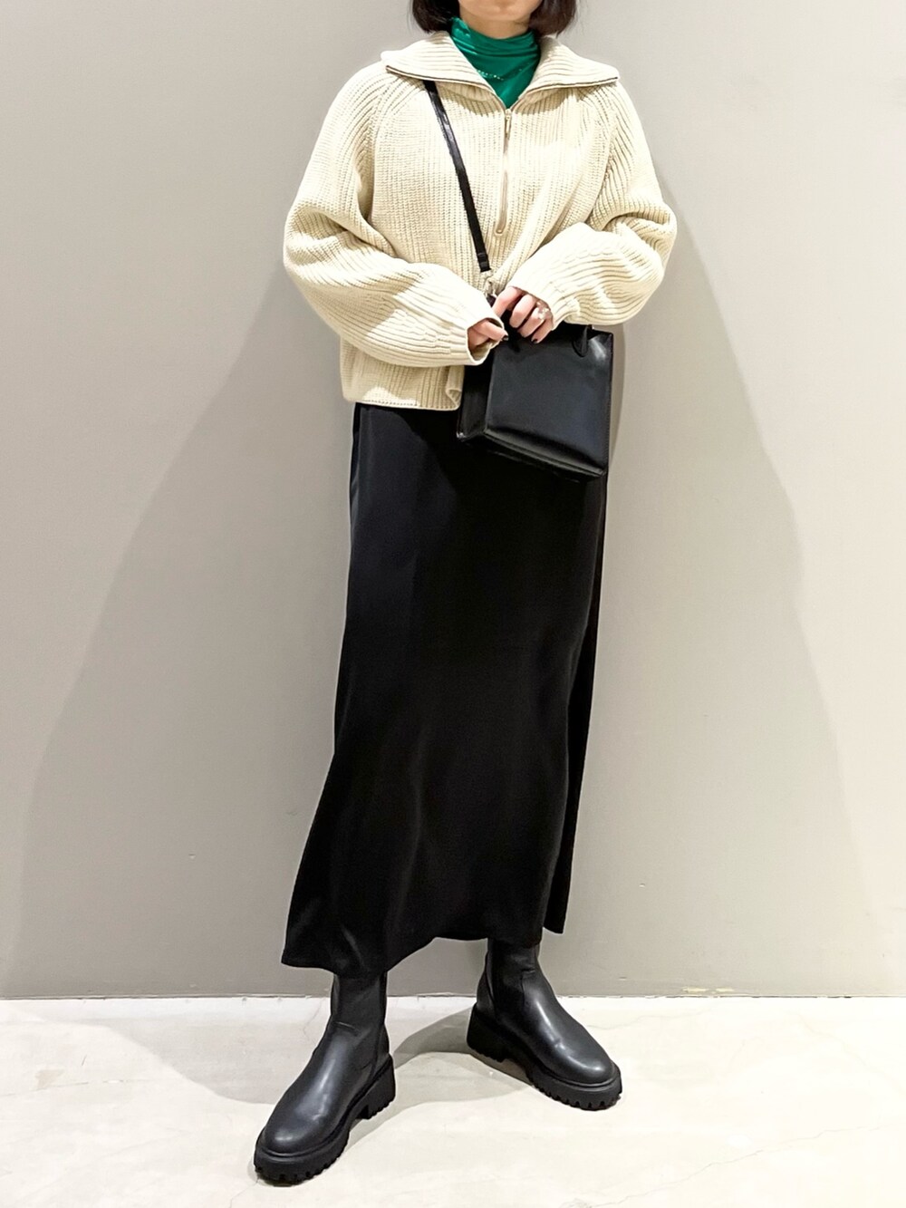 ブラック系のスカート、ブラック系のショルダーバッグ、ブラック系のブーツを着用したレディースの冬コーディネートの4枚目の写真