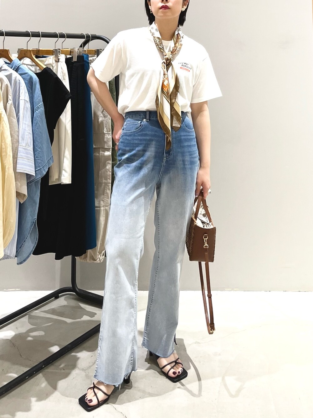 ブルー系のデニムパンツ、ブラック系のサンダル、ブラウン系のショルダーバッグを着用したレディースの夏コーディネートの5枚目の写真