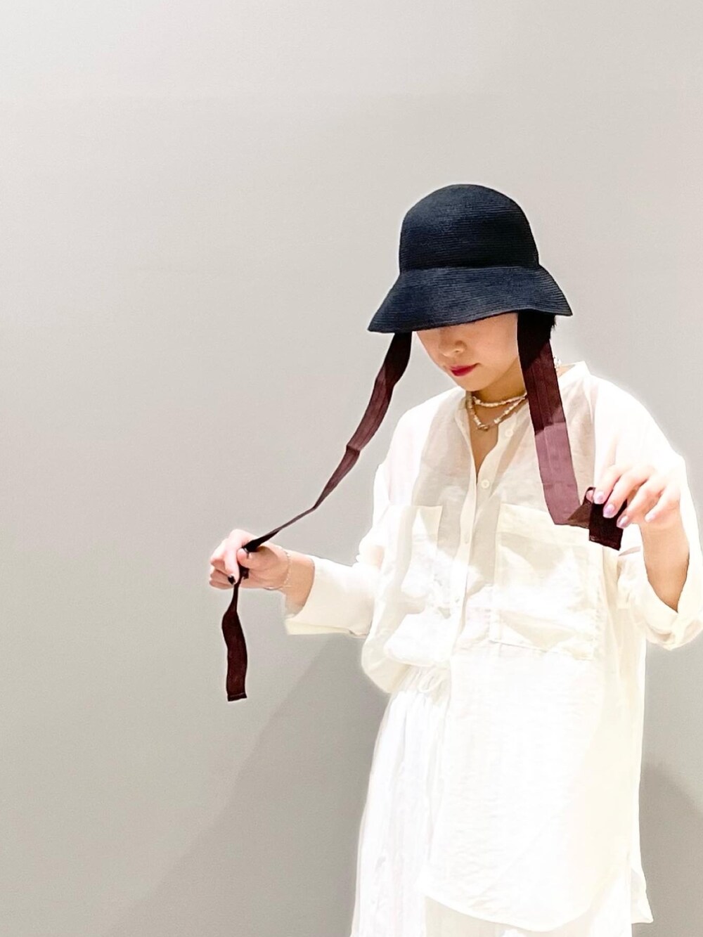 ホワイト系のスカート、ホワイト系のシャツ/ブラウス、ブラック系のサンダルを着用したレディースの夏コーディネートの3枚目の写真