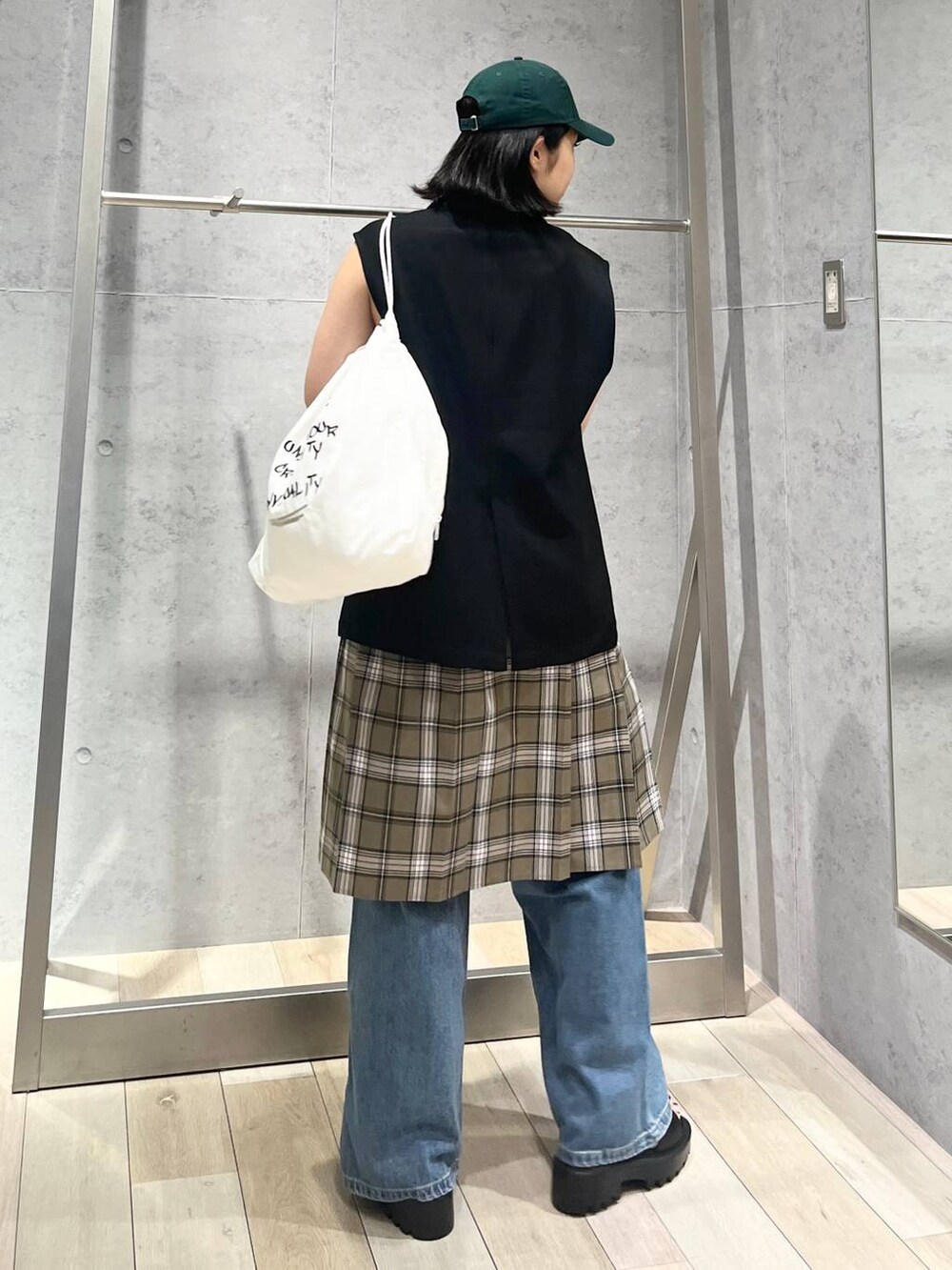 ホワイト系のタンクトップ、ブラック系のサンダル、ベージュ系のスカートを着用したレディースの秋コーディネートの4枚目の写真