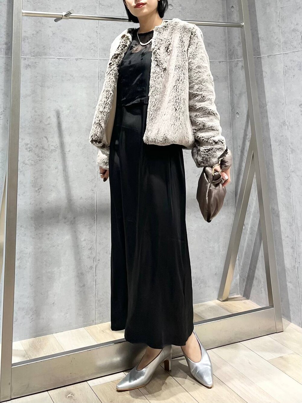 シルバー系のパンプス、ブラウン系のハンドバッグ、ベージュ系のノーカラーコートを着用したレディースの秋コーディネートの7枚目の写真