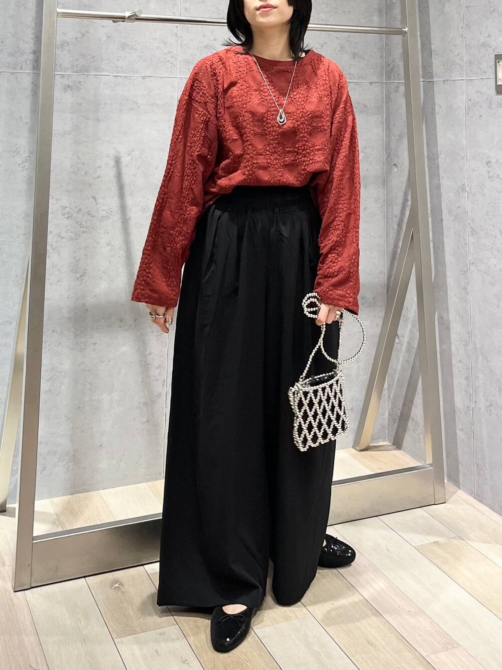 レッド系のTシャツ/カットソー、ブラック系のスラックス、シルバー系のショルダーバッグを着用したレディースの夏コーディネートの7枚目の写真