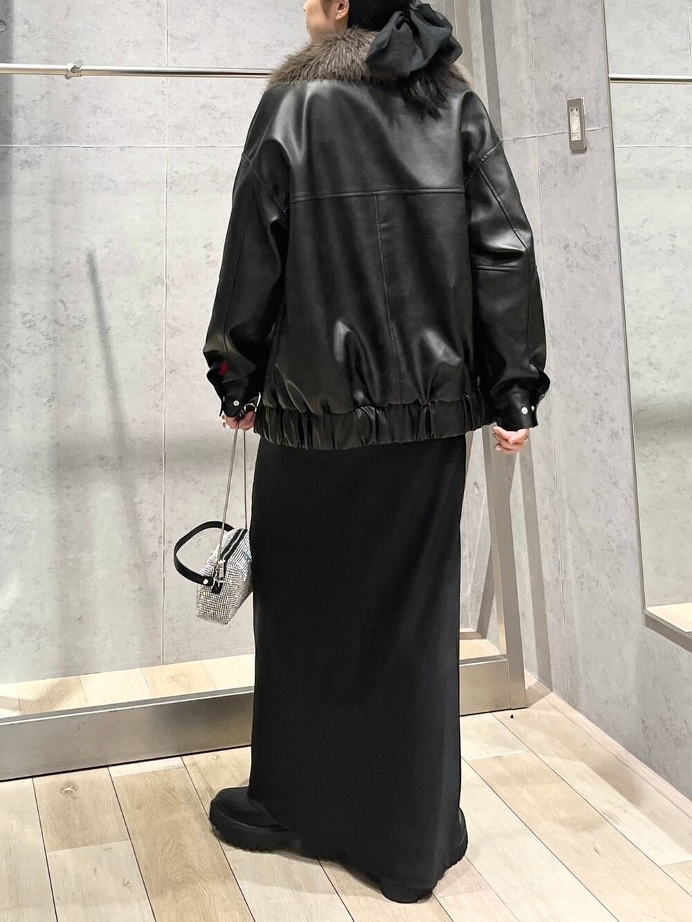 ブラック系のブーツ、オレンジ系のニット/セーター、ブラック系のスカートを着用したレディースの冬コーディネートの7枚目の写真