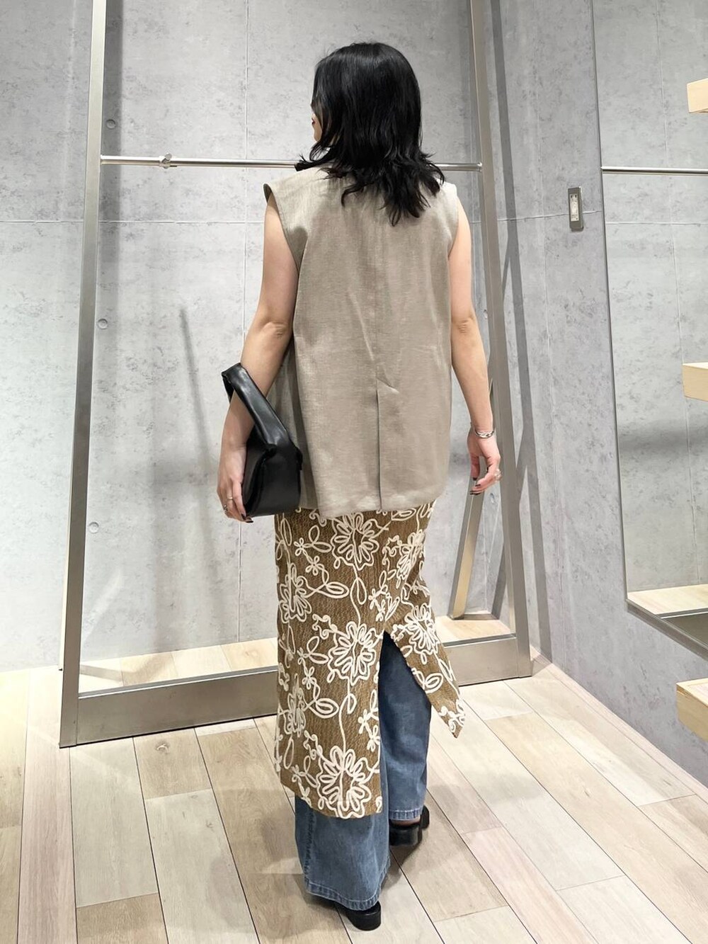 ブルー系のデニムパンツ、ブラック系のハンドバッグ、ブラック系のサンダルを着用したレディースの春コーディネートの4枚目の写真