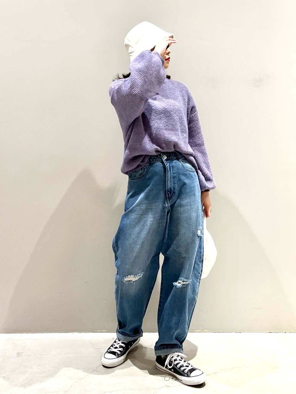 ホワイト系のバッグ、ブルー系のデニムパンツ、パープル系のニット/セーターを着用したレディースの冬コーディネートの3枚目の写真