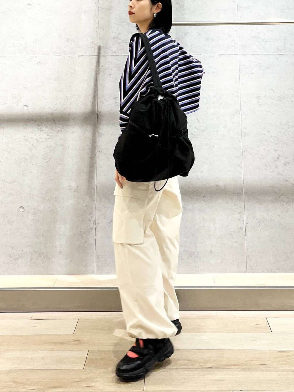 ブラック系のショルダーバッグ、ブルー系のTシャツ/カットソー、ホワイト系のカーゴパンツを着用したレディースの春コーディネートの5枚目の写真