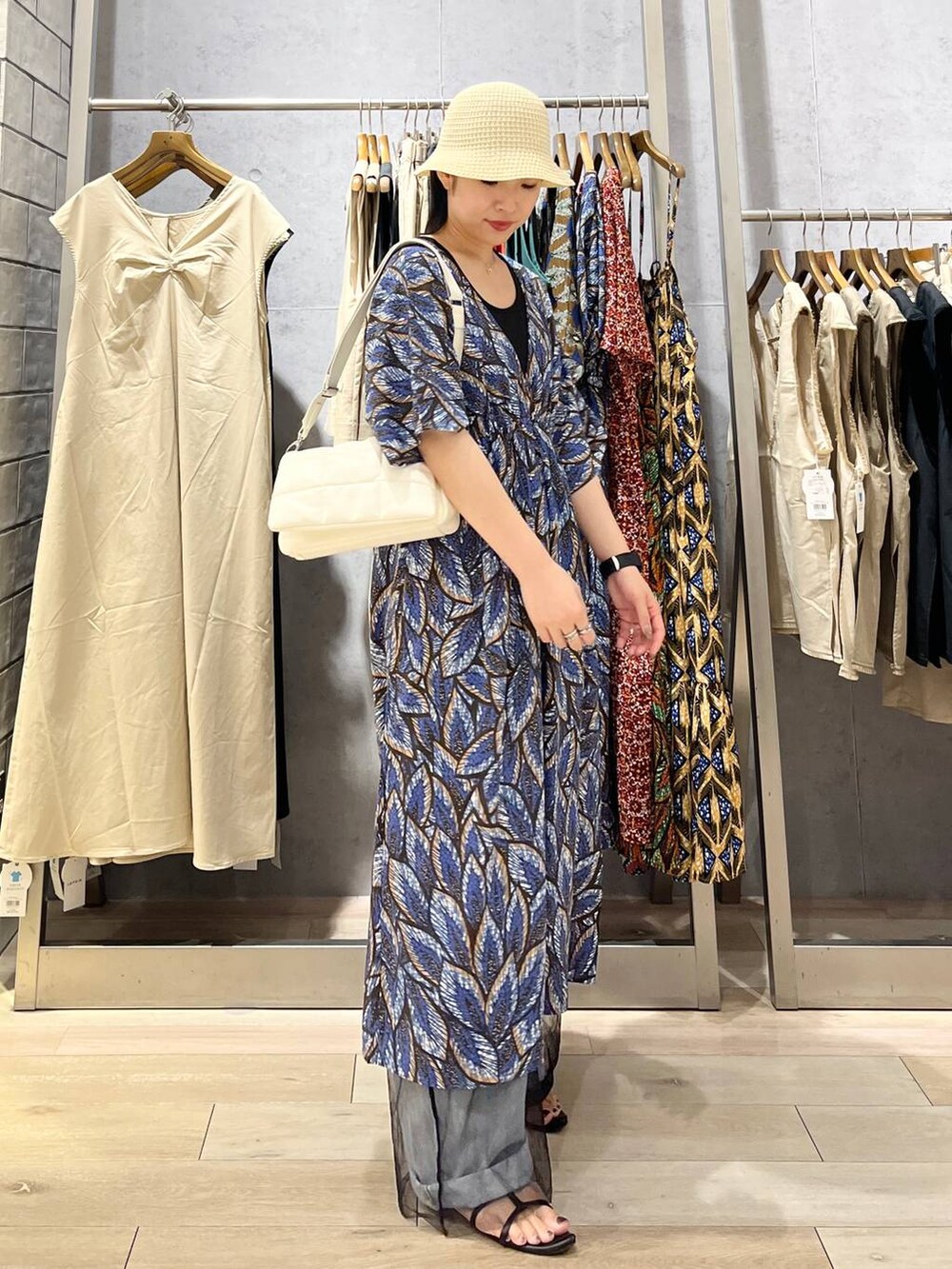 ホワイト系のショルダーバッグ、ブラック系のサンダル、ブルー系のデニムパンツを着用したレディースの夏コーディネートの5枚目の写真