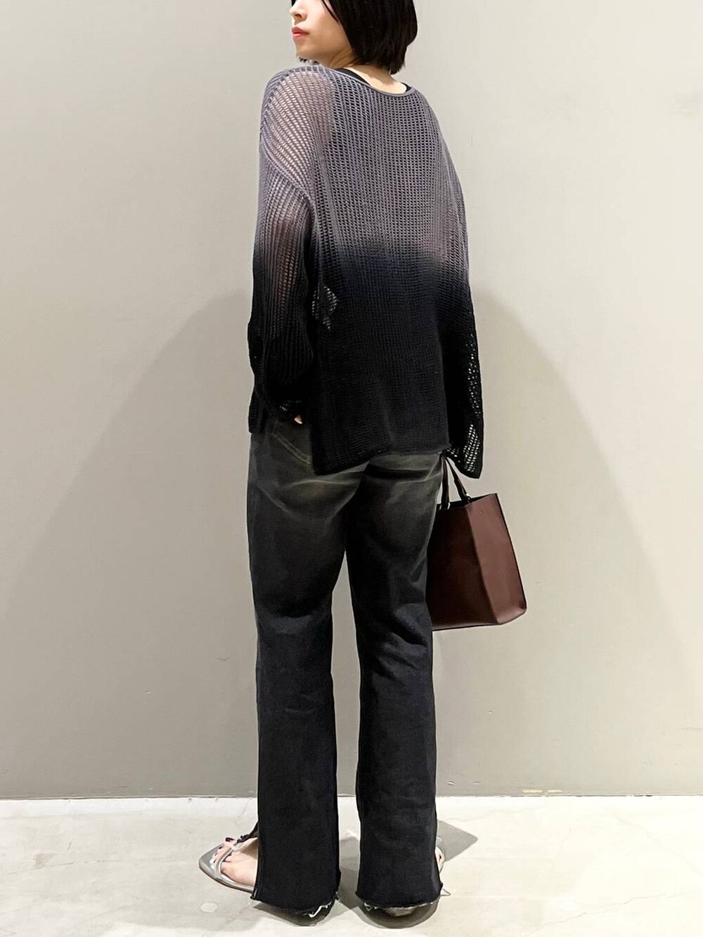 ブラック系のニット/セーター、シルバー系のサンダル、ブラック系のデニムパンツを着用したレディースの夏コーディネートの6枚目の写真