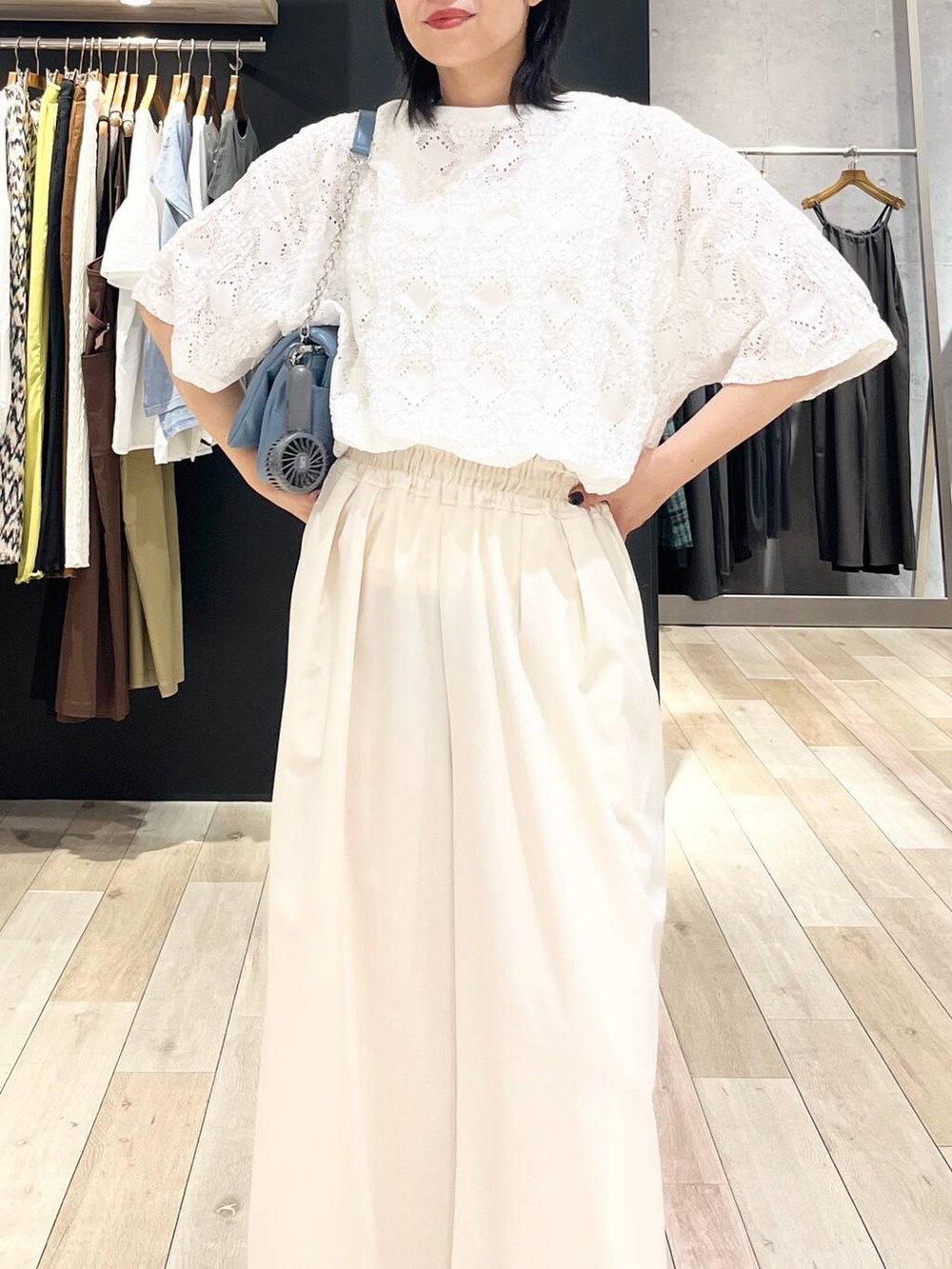 ブルー系のショルダーバッグ、ホワイト系のスラックス、ホワイト系のTシャツ/カットソーを着用したレディースの夏コーディネートの2枚目の写真