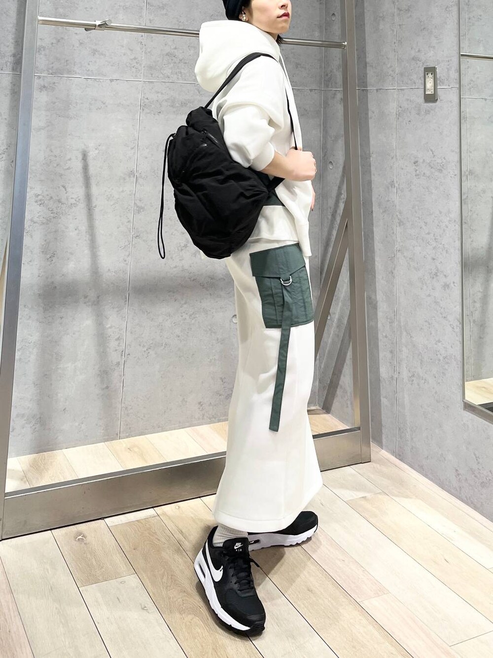 ブラック系のショルダーバッグ、ホワイト系のスカート、ホワイト系のパーカーを着用したレディースの冬コーディネートの3枚目の写真