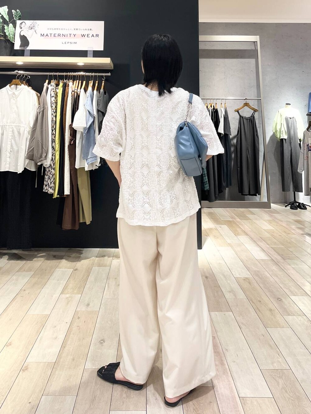 ブルー系のショルダーバッグ、ホワイト系のスラックス、ホワイト系のTシャツ/カットソーを着用したレディースの夏コーディネートの3枚目の写真