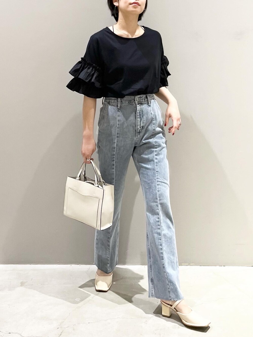 ブルー系のデニムパンツ、ホワイト系のショルダーバッグ、ホワイト系のパンプスを着用したレディースの夏コーディネートの2枚目の写真