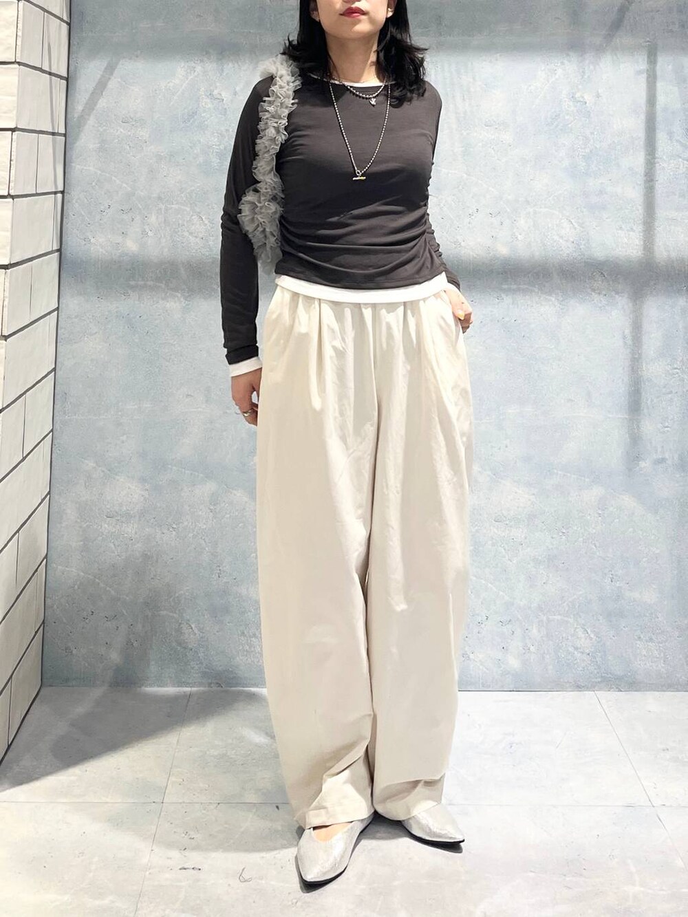 グレー系のショルダーバッグ、グレー系のTシャツ/カットソー、シルバー系のパンプスを着用したレディースの春コーディネートの3枚目の写真