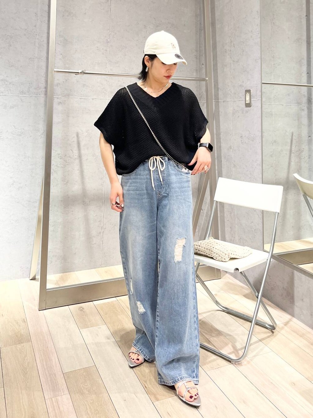 シルバー系のサンダル、ブラック系のニット/セーター、ブルー系のデニムパンツを着用したレディースの春コーディネートの4枚目の写真