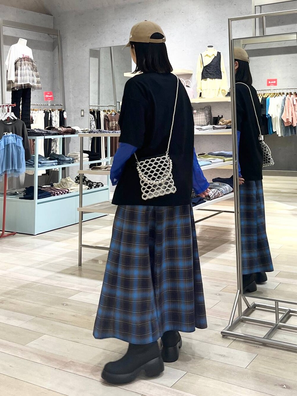 シルバー系のショルダーバッグ、ブラック系のレインシューズ、ブラック系のTシャツ/カットソーを着用したレディースの秋コーディネートの3枚目の写真